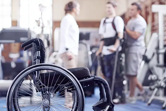 Empty wheelchair with patient and physical therapist in the background